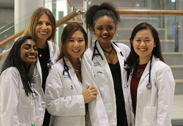 Students pose together wearing their white coats.